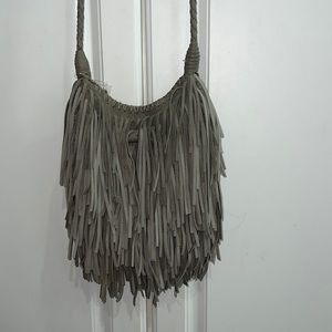 Gray fringe crossbody bag. Button closure with toggle. Inside zippered pocket.